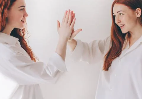 Two red-haired sisters stand isolated on a white background in spacious Stock Photos