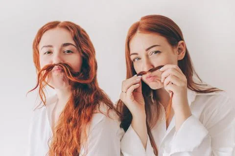 Two red-haired sisters stand isolated on a white background in spacious Stock Photos
