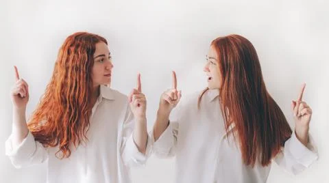 Two red-haired sisters stand isolated on a white background in spacious Stock Photos