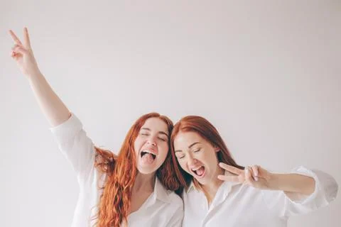 Two red-haired sisters stand isolated on a white background in spacious Stock Photos