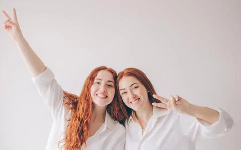 Two red-haired sisters stand isolated on a white background in spacious Foto stock