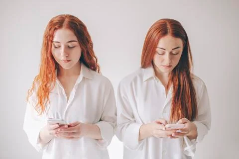 Two red-haired sisters stand isolated on a white background in spacious Stock Photos