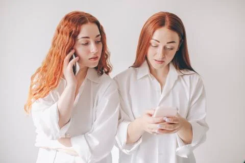 Two red-haired sisters stand isolated on a white background in spacious Stock Photos
