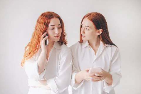 Two red-haired sisters stand isolated on a white background in spacious Stock Photos