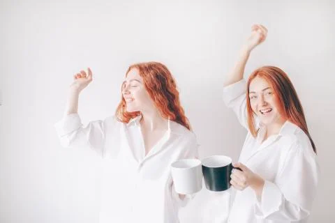 Two red-haired sisters stand isolated on a white background in spacious Stock Photos