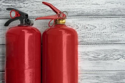 Two red hand extinguishers on a light wooden background. Copy space Stock Photos