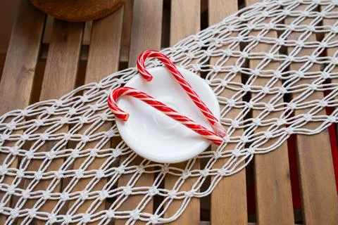Two red hard candy canes striped on white plate on rustic wooden table Stock Photos