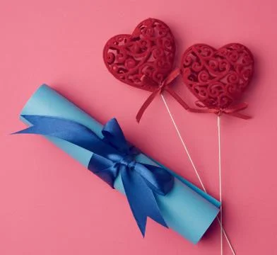 Two red heart and roll of blue paper tied with a silk blue ribbon Stock Photos