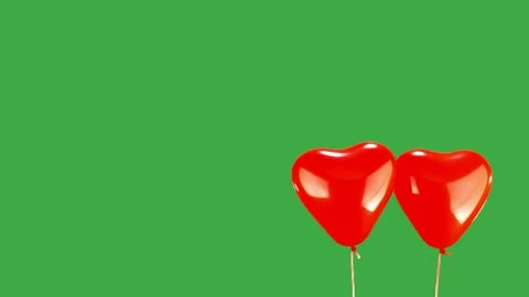 Two red heart shaped balloons rising and falling on green screen slow motion Stock Footage 284012045