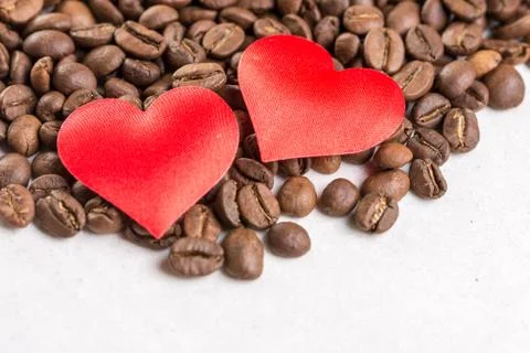 Two red hearts on the coffee beans pile with copy space above white marble ba Stock Photos