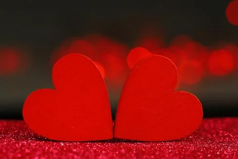 Two red hearts on a dark background with glare and blurred lights. Stock Photos