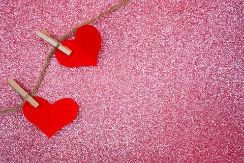 Two red hearts on pink glitter background Stock Photos