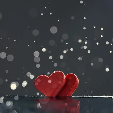 Two red hearts with rain drops reflected in the water on a dark background .. Stock Photos