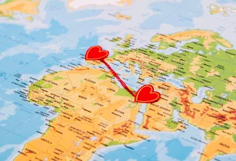 Two red hearts on a world map connected by a red thread Stock Photos