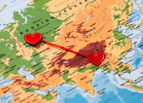 Two red hearts on a world map connected by a red thread Stock Photos