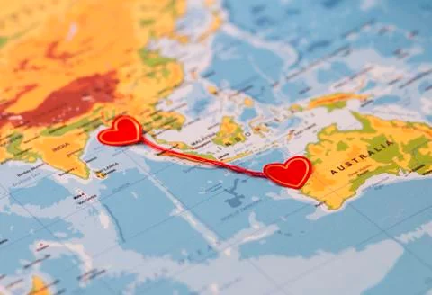 Two red hearts on a world map connected by a red thread Stock Photos