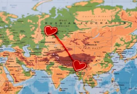 Two red hearts on a world map connected by a red thread Stock Photos