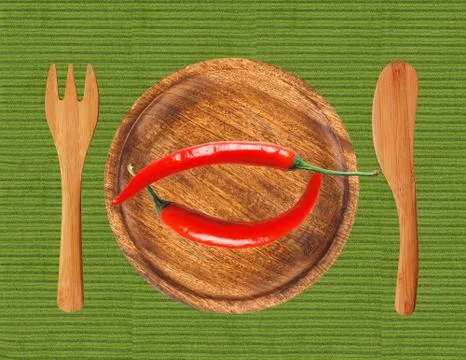Two red hot chilli peppers on wooden plate over green cloth Photos