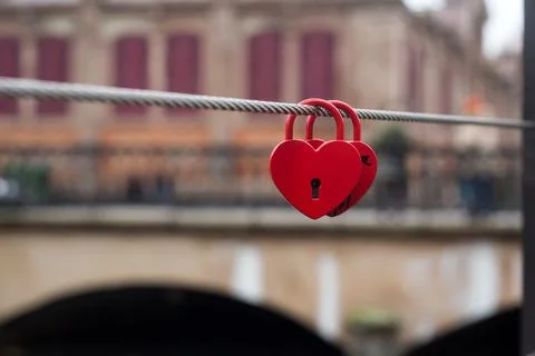 Two red padlocks in shaped heart on metallic cable in border water Stock Photos