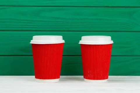 Two red paper cardboard coffee Cup on green background Stock Photos