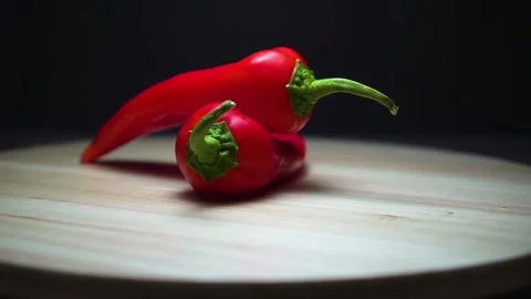 Two red peppers on a black background. Wooden plank. Base rotation. Stock Footage 169464768