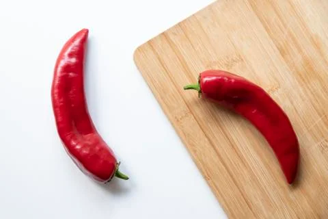 Two red peppers on a cutting board with white background Stock Photos