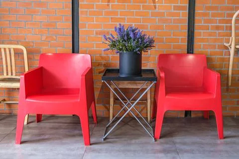 Two red plastic armchairs and decorative bouquet of artificial lavender flowe Foto stock
