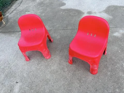 Two red plastic chairs on a concrete surface. 스톡 사진