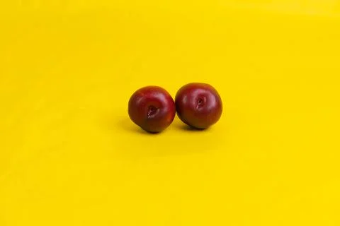 Two red plums on yellow background Stock Photos