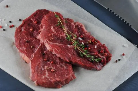 Two red raw beef steak on paper with spices - top view Stock Photos