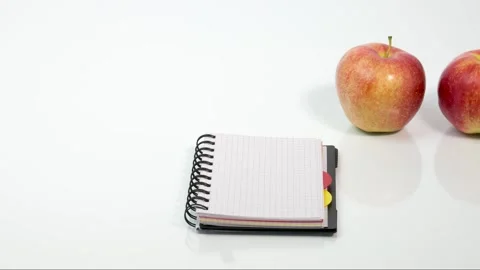 Two red ripe apples, a bottle of water, a pen and a notebook Stock Footage 181063330