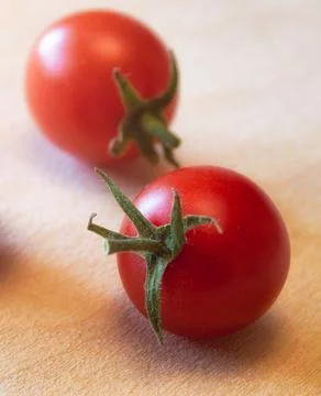 Two red ripe small cherry tomatoes in the light Stock Photos
