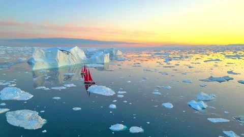 Two red sailboats navigating around Arctic icebergs at sunrise Stock-Footage 341327955