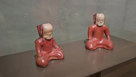 Two Red Seated Clay Figures, Casa del Alabado, Quito, Ecuador 8K Stock Footage 331493299
