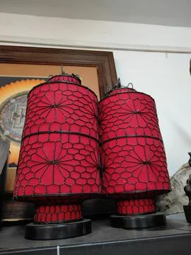 Two red spider-web-patterned lamps with black metal frames, sitting on top .. Stock Photos