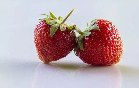 Two red strawberries on a white background Stock Photos