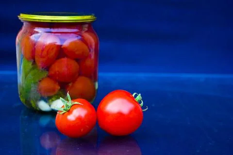 Two red tomatoes against a background of pickled tomatoes. Stock Photos