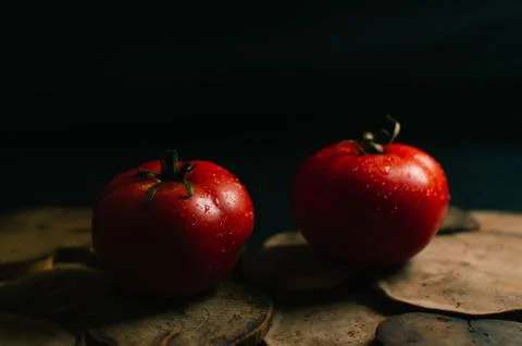 Two red tomatoes on a black background, middle plan Stock Photos