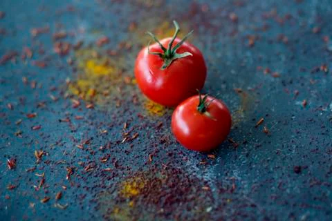 Two red tomatoes on blue surface with spices Foto stock