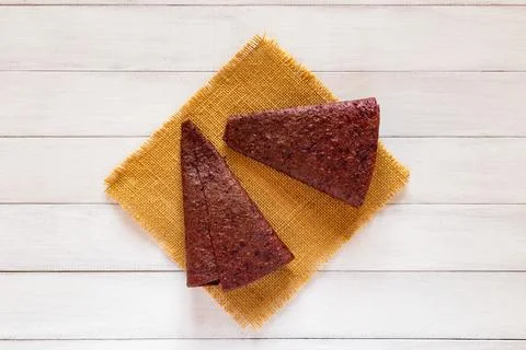 Two red triangular fruit pastille pieces displayed on yellow fabric over wh.. Stock Photos