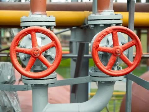 Two red valves with red steering wheels over background of pipes at chemical  Stock Photos