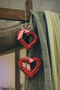 Two red wicker hearts on a thread on a linen background Стоковые фото