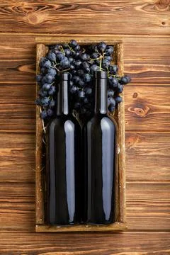 Two Red Wine bottles composition on brown wooden table. Red wine bottles in box Stock Photos