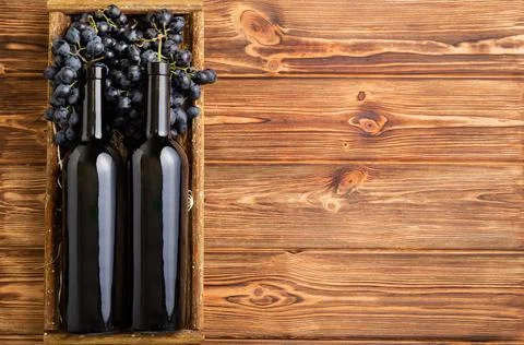Two Red Wine bottles composition on brown wooden table. Red wine bottles in box Stock Photos