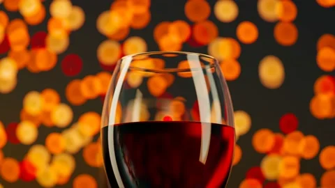 Two red wine glasses filled with alcohol. Many colourful lights in the distance. Stock Footage 201183238