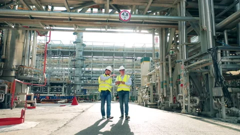 Two refinery inspectors are passing by pipelines while talking Stock Footage 163281985