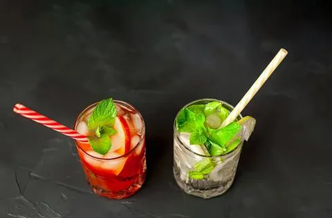 Two refreshing berry and mint drinks with straws on black Stock Photos