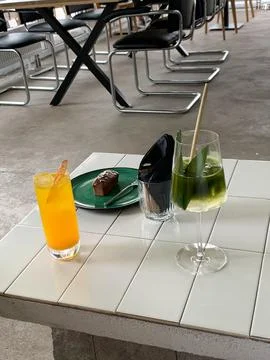 Two refreshing drinks and a chocolate dessert served on a tiled table Stock Photos