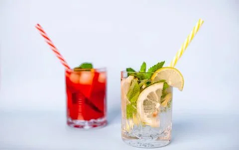 Two refreshing fruit drinks with lemon and mint in glasses Stock Photos