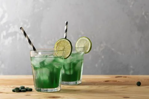 Two refreshing green drinks with ice, chlorella, and spirulina in glass tum.. Stock Photos